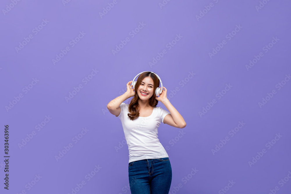 Pretty Asian woman dancing and listening to music on headphones - obrazy, fototapety, plakaty 