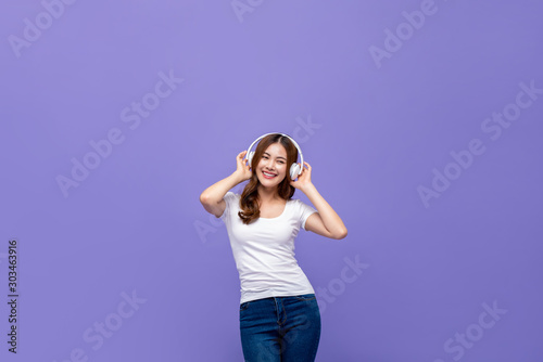 Pretty Asian woman dancing and listening to music on headphones