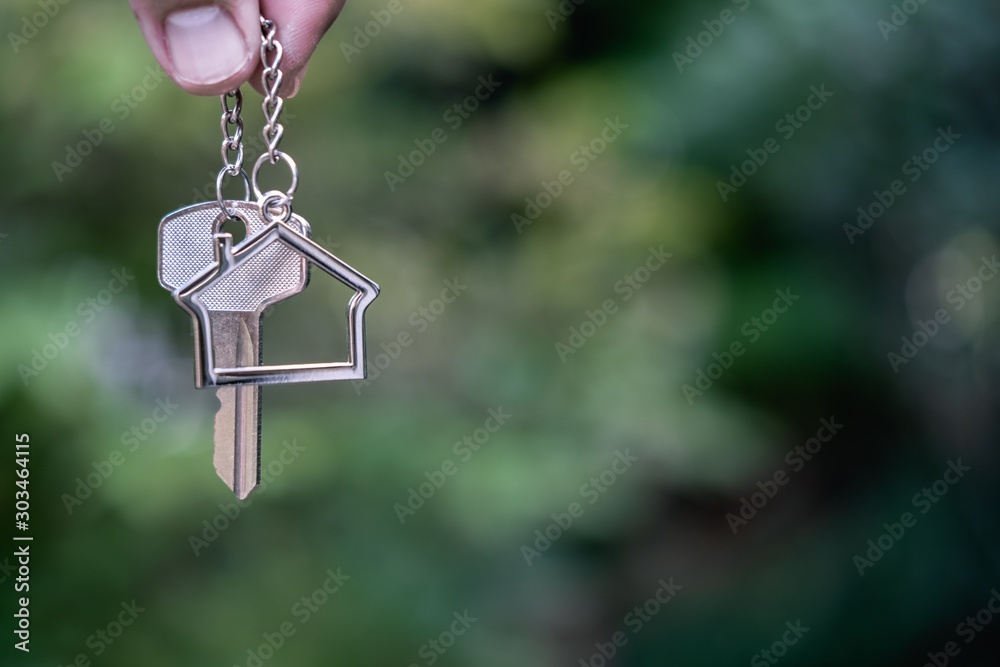 Home key with house keyring giving with blur house background Home key with house keyring giving with blur house background