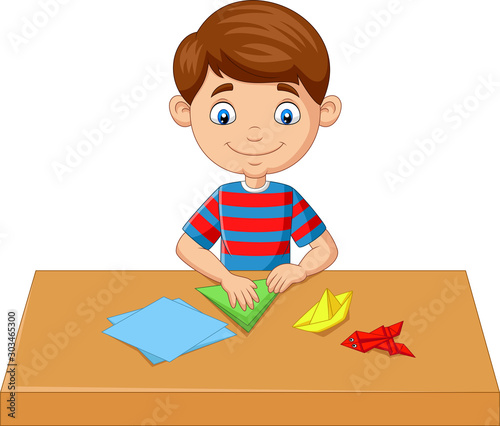Little boy folding paper and making origami toys