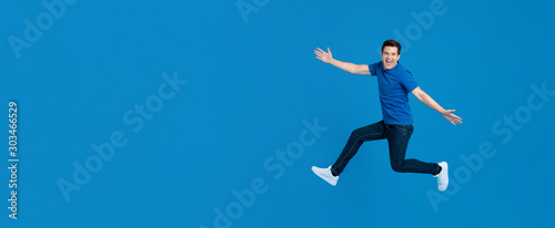 Energetic young man jumping and smiling with outstretched hands