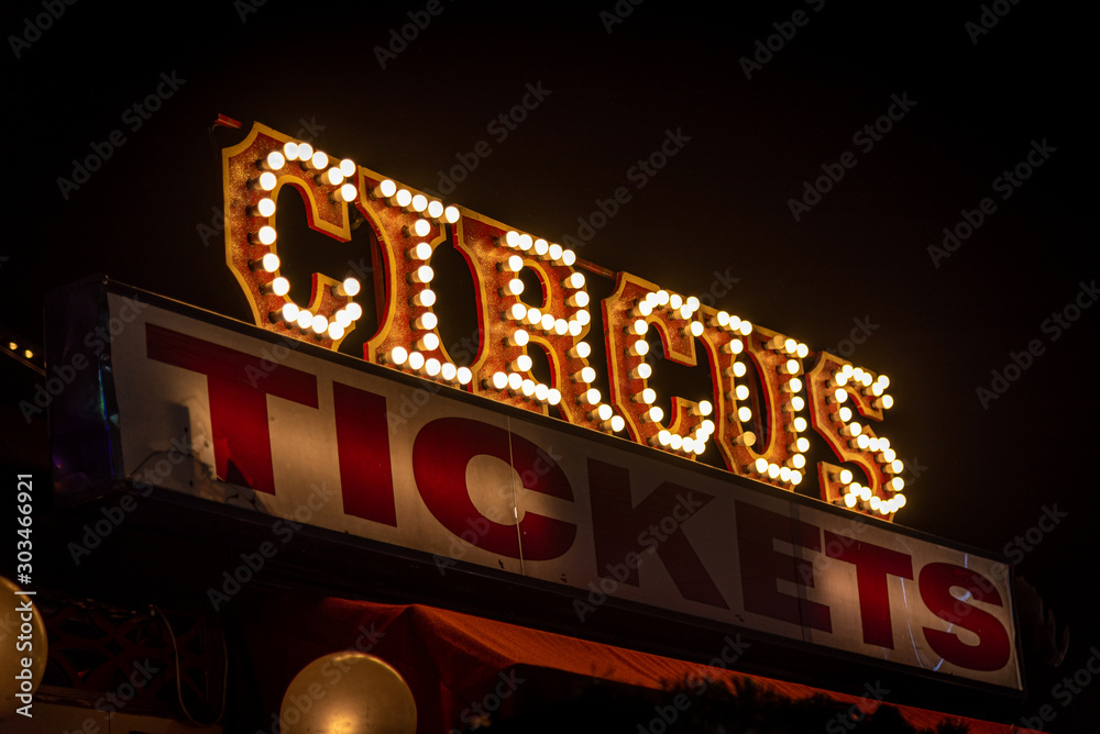 Old dimly lit circus sign with light bulbs in the dark over a ticket stand. Typical view of an entrance to a circus. Concept of fun, family and joy.