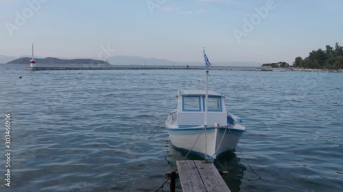A small boat in the Aegean sea water and a small dock in the port of Limerias in Thasos, Greece. photo