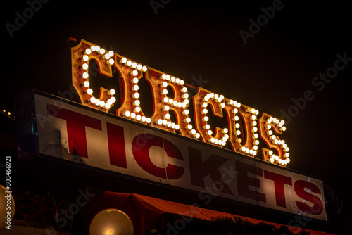Old dimly lit circus sign with light bulbs in the dark over a ticket stand. Typical view of an entrance to a circus. Concept of fun, family and joy.