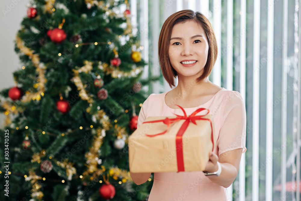 Portrait of young pretty Asian woman outstretching hands with Christmas gift Portrait of young pretty Asian woman outstretching hands with Christmas gift