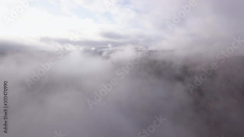Aerial, drone shot, panning through fog, over hills and foliage forest, on a foggy, autumn day, in Flakk, Aust-Agder, South Norway photo