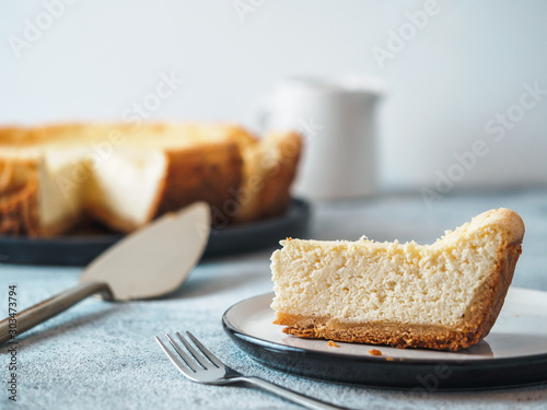 Plate with piece of cheesecake on tabletop. Classic homemade cheesecake with Shallow DOF. Copy space for text. photo