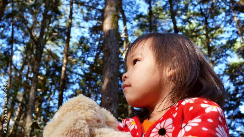 Asian little child girl looking around while going camping with family on bright sky background. The concept of outdoor activities and adventures in nature for kids. Asian little child girl looking around while going camping with family on bright sky background. The concept of outdoor activities and adventures in nature for kids.