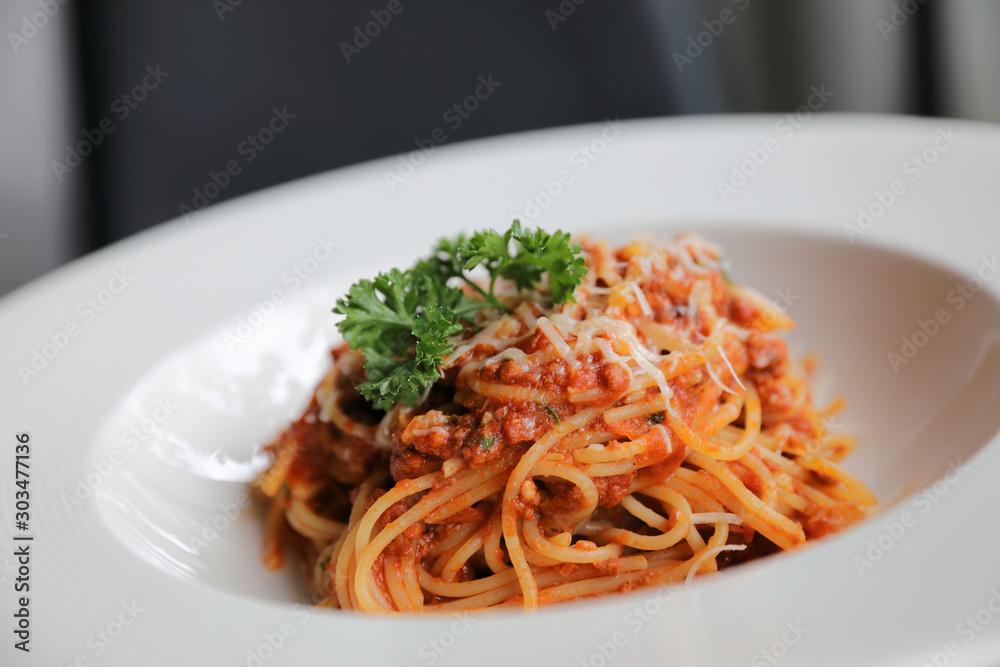 spaghetti Bolognese with minced beef and tomato sauce garnished with parmesan cheese and basil , Italian food