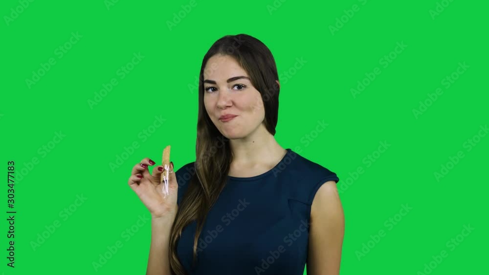 Sexy attractive girl eating a biscuit in front of a green screen Sexy attractive girl eating a biscuit in front of a green screen