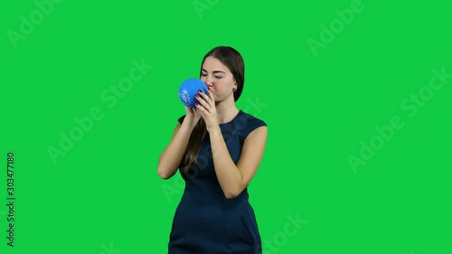 Girl blowing up a balloon in front of a green screen photo