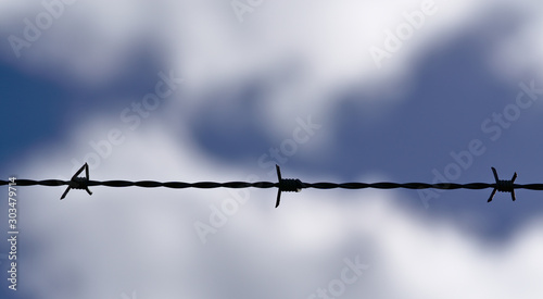 Line of barb wire with sky softly blurred in background