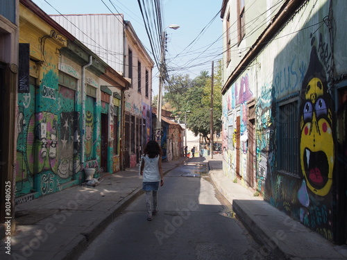 A woman walking through the city with beautifully designed walls and streets, Colorful houses and streets of the port city, Valparaiso, Chile © Mithrax