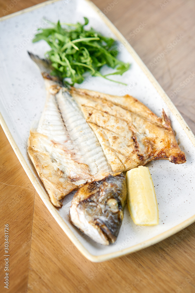 Plate Dorado with arugula and lemon. BBQ seafood. Restaurant menu Plate Dorado with arugula and lemon. BBQ seafood. Restaurant menu