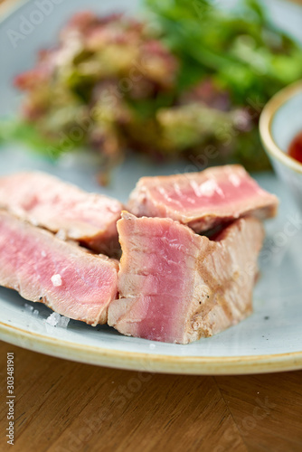 Closeup Medium rare tuna with lettuce and hot sauce. Restaurant menu