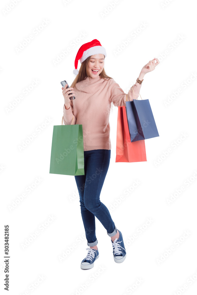Full length of Beautiful asian girl wearing santa claus hat ,carrying many paper shopping bags and smartphone isolated over white background. Full length of Beautiful asian girl wearing santa claus hat ,carrying many paper shopping bags and smartphone isolated over white background.
