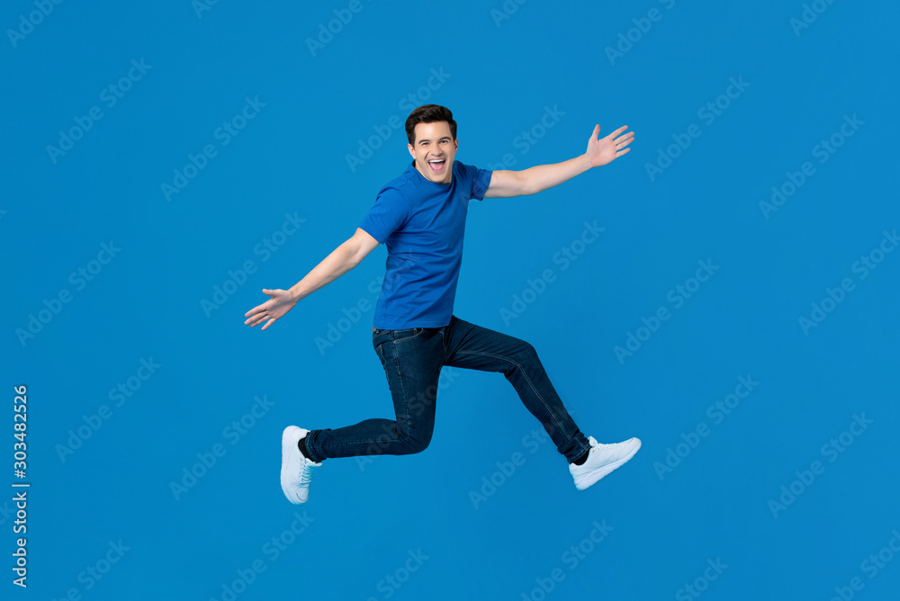 Energetic handsome man jumping and smiling with outstretched hands
