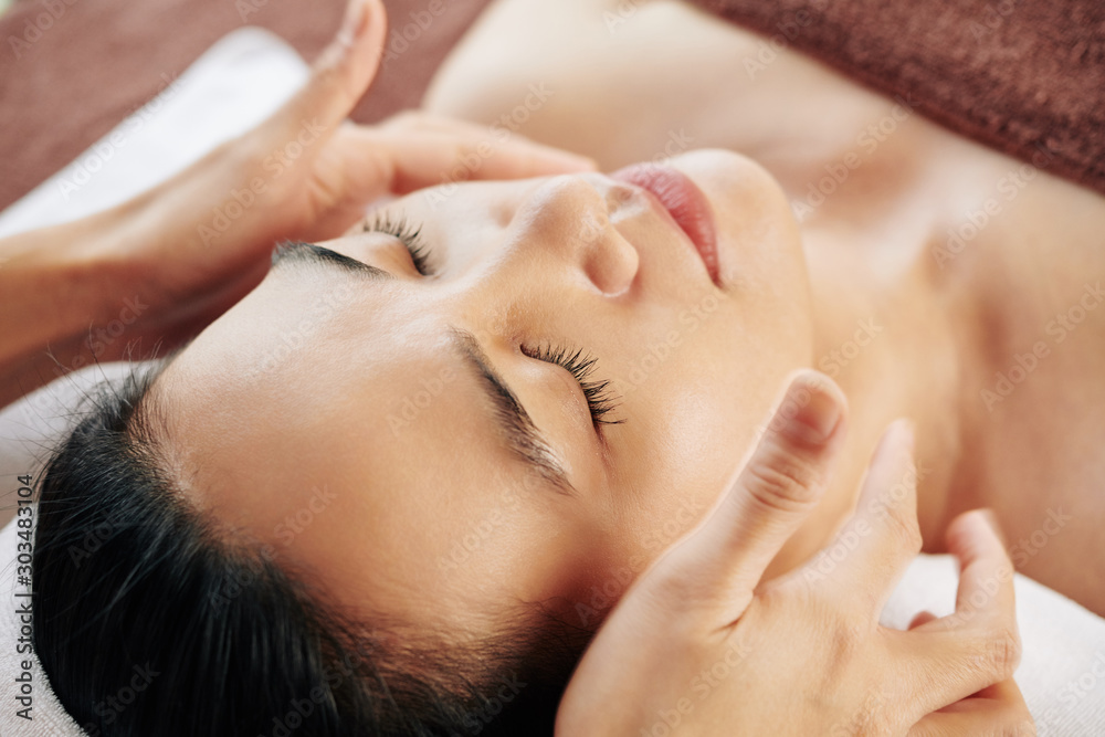 Φωτογραφία Relaxed young Asian woman enjoying relaxing anti-aging face massage in beauty sa