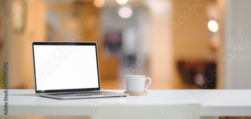 Comfortable workplace with mock up laptop computer and coffee cup with office background © bongkarn