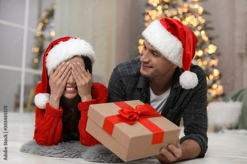 Man presenting Christmas gift to his girlfriend at home Man presenting Christmas gift to his girlfriend at home