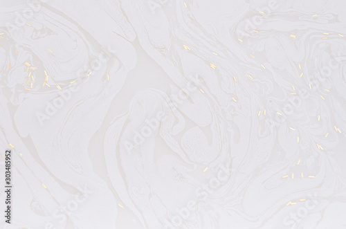 Soft light white abstract background of liquid paint and gold glitter on surface as abstract texture.