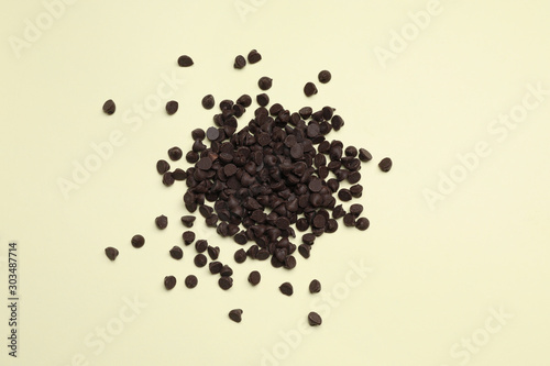Pile of delicious chocolate chips on beige background, top view