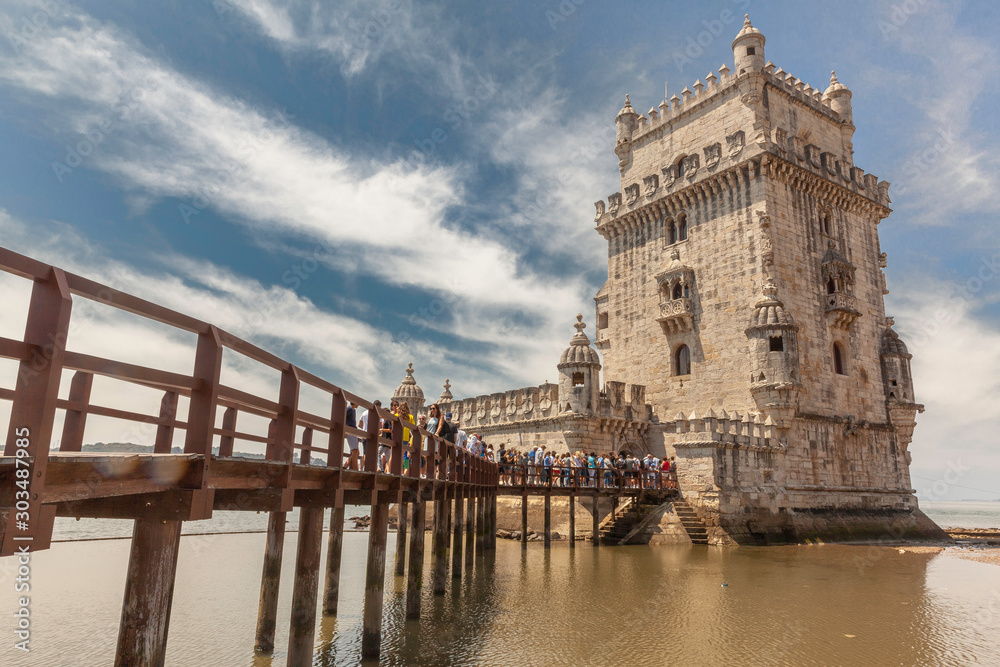 Scenic Belem Tower and wooden bridge with crowd of tourists in Lisbon, Portugal