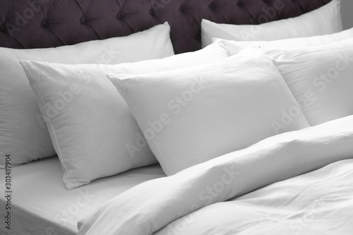 Modern bed with soft pillows in room photo