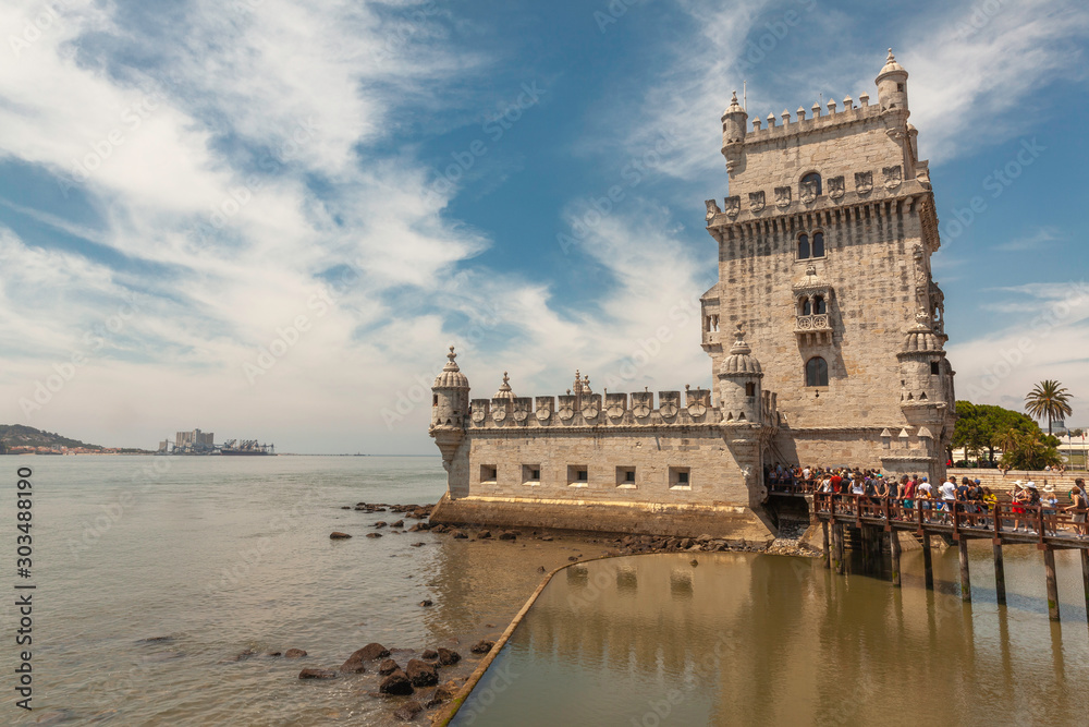 Scenic Belem Tower and wooden bridge with crowd of tourists on the river Tagus (Tajo) in Lisbon, Portugal