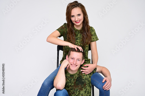 Family Relationship Concept. Portrait of a pleasant young pretty happy family: a brunette girl with a beautiful hairstyle and a guy in uniform on a white background.