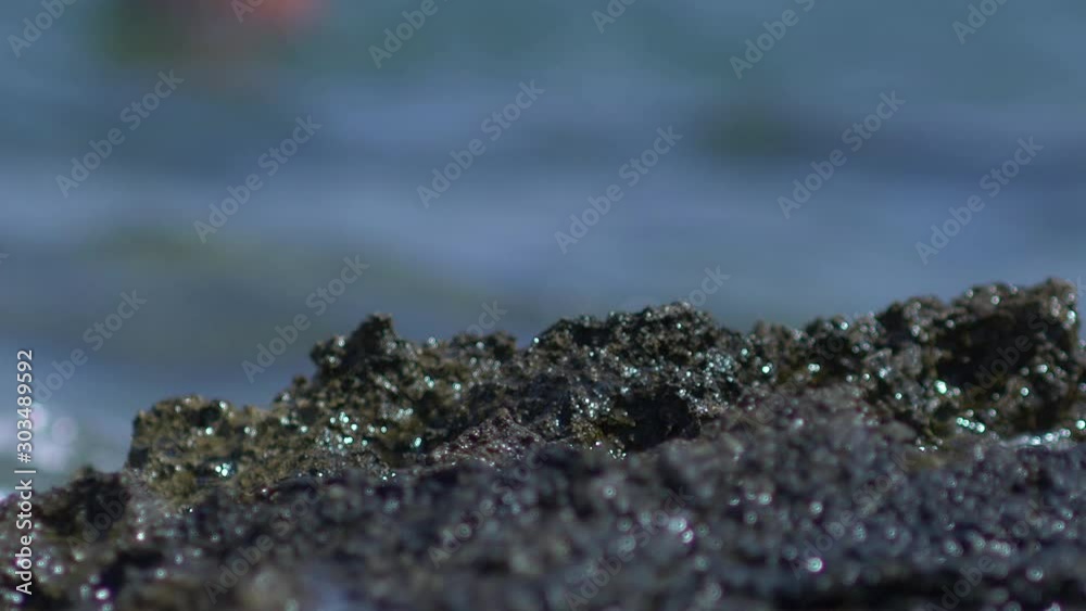Rock near the sea and water crushing against it in slow motion. Close up of the ocean waves hitting the rocks on the shore. Rock near the sea and water crushing against it in slow motion. Close up of the ocean waves hitting the rocks on the shore.