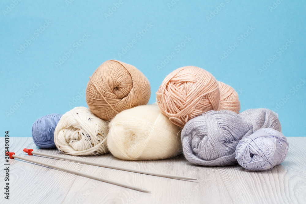 Woolen yarn for knitting. Balls of natural wool yarn and knitting needles Woolen yarn for knitting. Balls of natural wool yarn and knitting needles