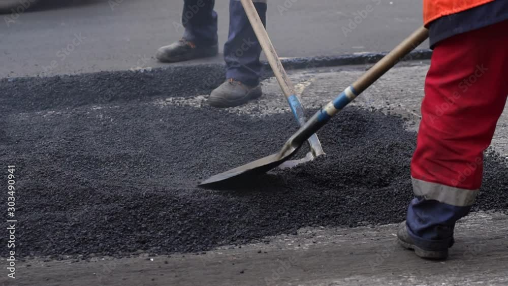 Workers on a road construction, industry and teamwork. Fresh asphalt construction. Bad road. Roller and workers on asphalting and repair of city streets. Close-up. Workers on a road construction, industry and teamwork. Fresh asphalt construction. Bad road. Roller and workers on asphalting and repair of city streets. Close-up.