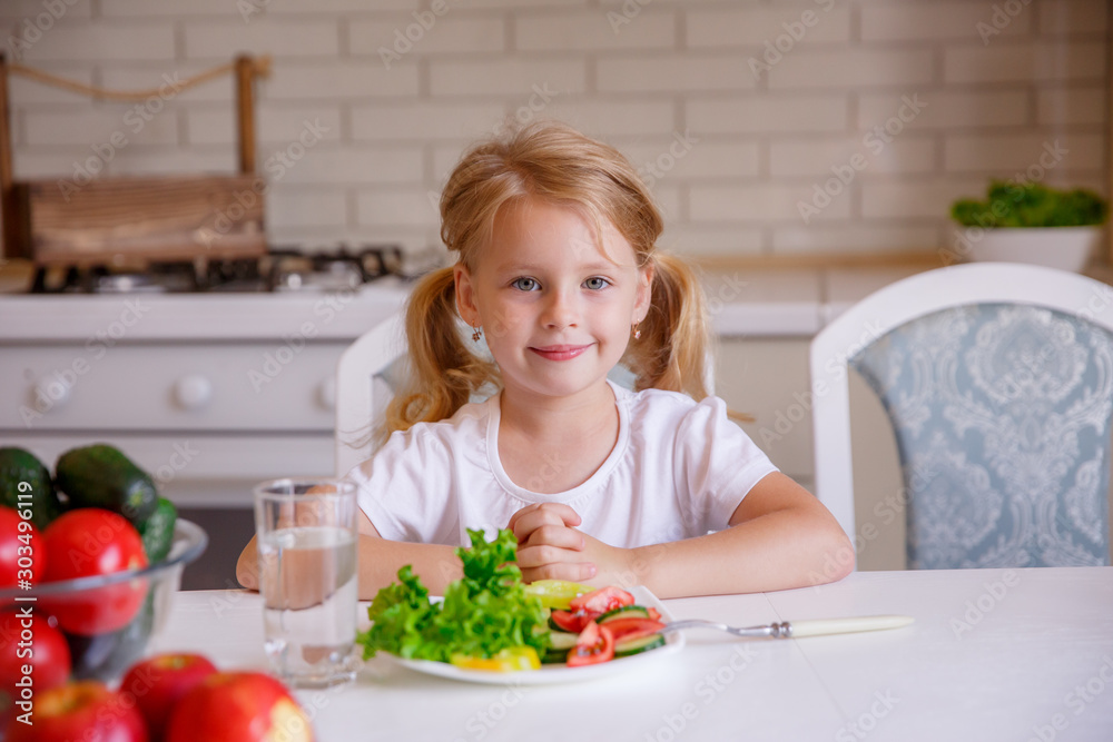 blonde baby girl eating vegetables in the kitchen blonde baby girl eating vegetables in the kitchen