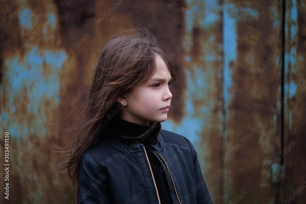 serious young girl in a black leather jacket against a rusty wall serious young girl in a black leather jacket against a rusty wall