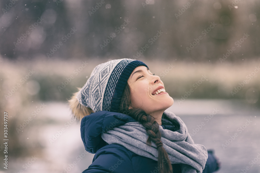 Φωτογραφία Winter woman happy enjoying snow falling on face outdoor forest nature Asian girl looking up wearing hat and scarf cold weather clothes