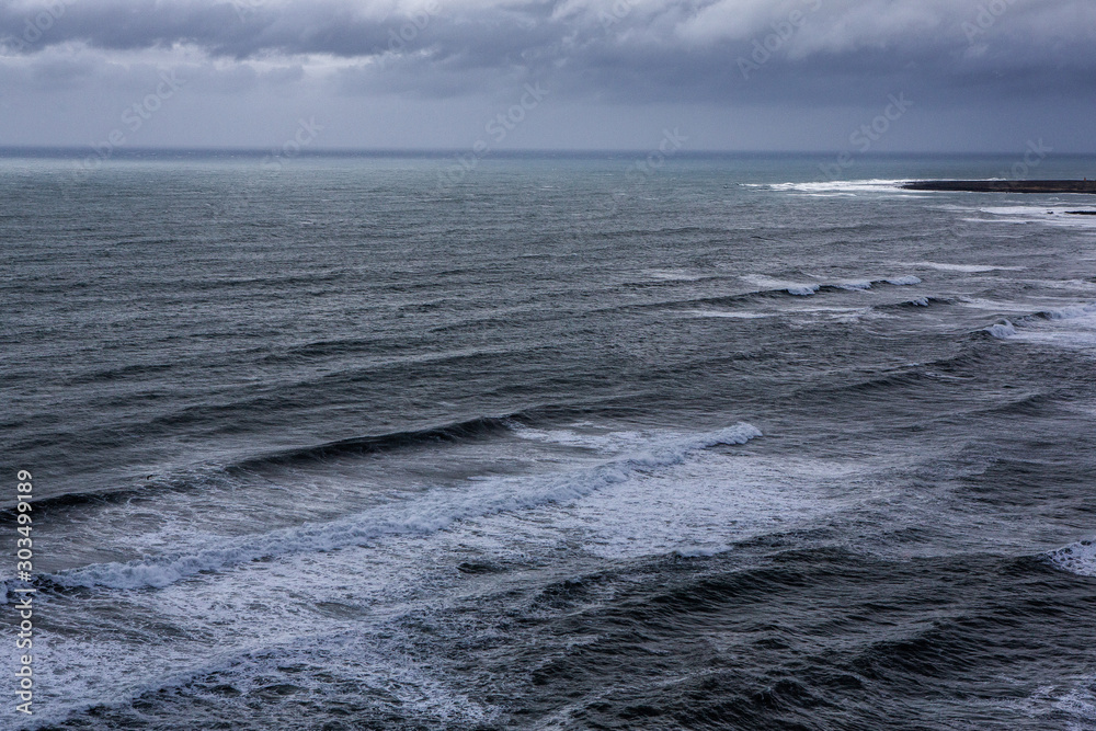 Beautiful coast of the Atlantic ocean with mountains. Waves of the North Atlantic ocean crashing against the beach in iceland after a storm.