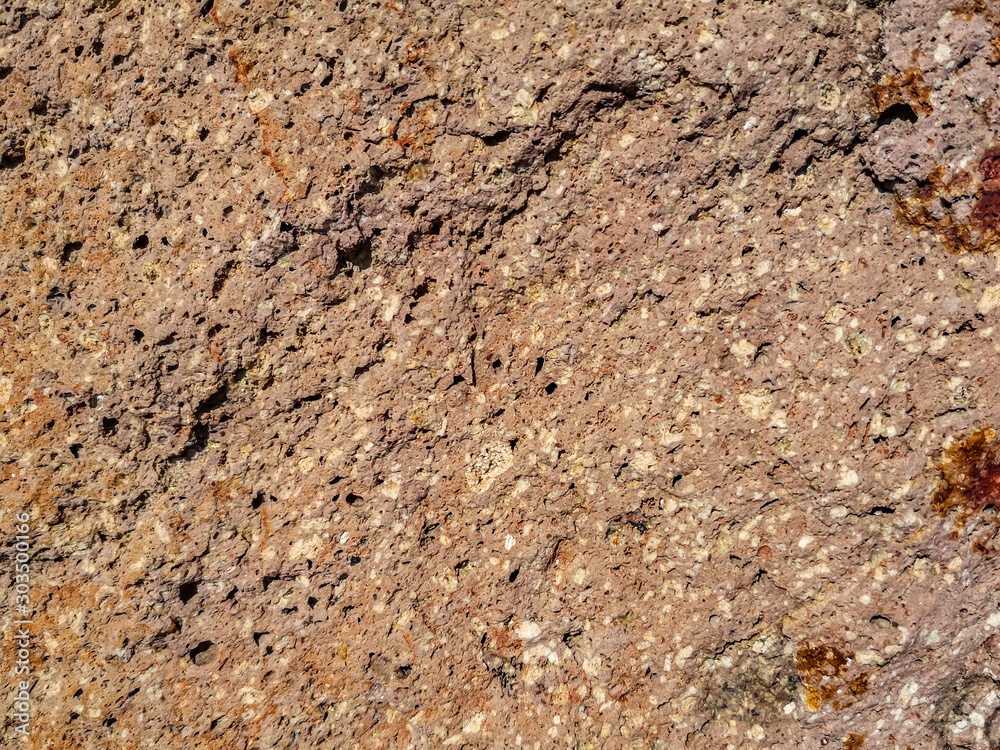 Texture of pink-orange granite or cinder surface. Beautiful pattern of multi-colored crumbs, interspersed and dots Texture of pink-orange granite or cinder surface. Beautiful pattern of multi-colored crumbs, interspersed and dots