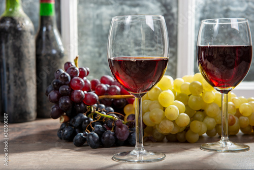 Composition with two wineglasses, grapes and bottles of red wine