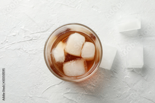 Glass of whiskey with ice cubes on white background  top view