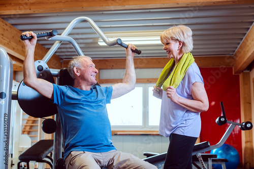 Fototapeta Naklejka Na Ścianę i Meble -  Senior man in the gym with his wife on exercise machines
