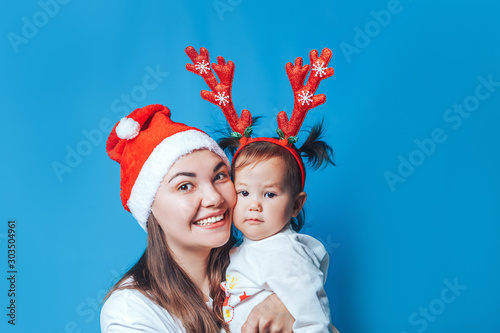 Happy smilind mother and her doughter baby girl hugging and lookind at camera, waiting christmas.