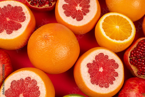 Grapefruit  orange  pomegranate  citrus sweetie on red background.