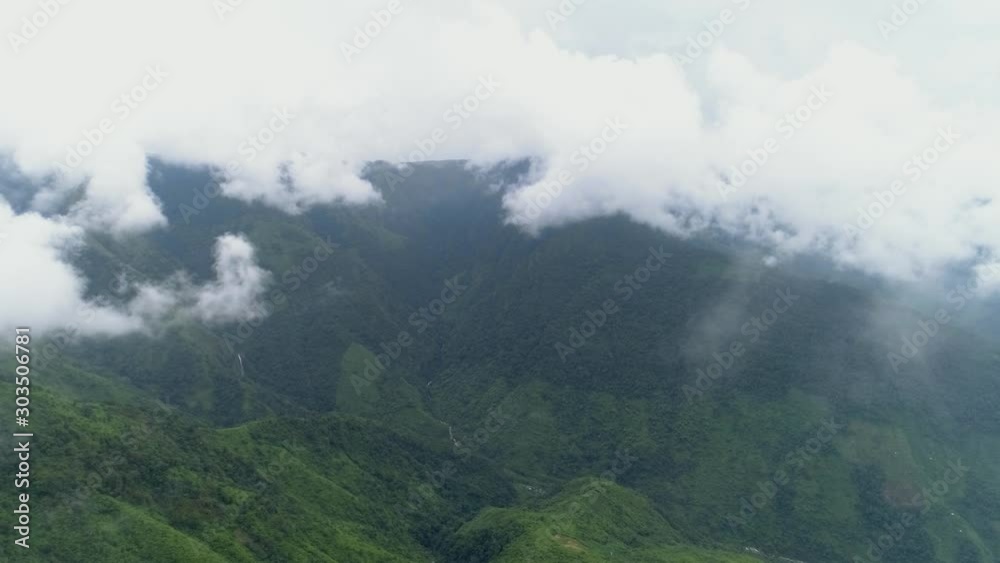 Beautiful clouds covering mountains with steep slopes and green hills with lush vegetation, drone footage Beautiful clouds covering mountains with steep slopes and green hills with lush vegetation, drone footage