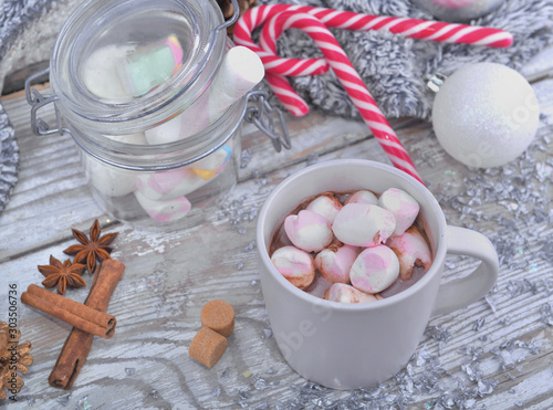 mug full of marshmallows on a milk chocolate with spices and christmas decoration