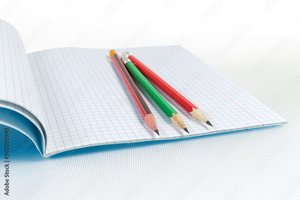 Sharply sharpened graphite pencils on open exercise book close-up Sharply sharpened graphite pencils on open exercise book close-up