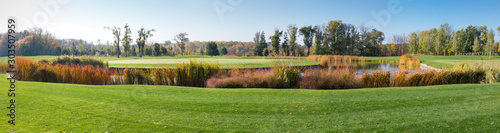 Fotografie Panoramic view of large lawn with pond against autumn forest