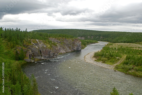 View from the high bank to the bend of the northern mountain river Kozhim. A high cliff on one side of the river and a gentle wooded shore on the other side. Subpolar Ural, Yugyd Va National Park photo