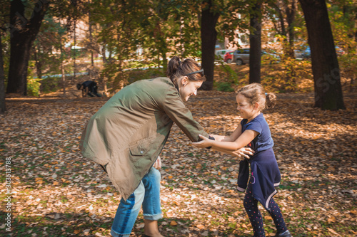 Happy mother and daughter playing in autumn park. © LumineImages