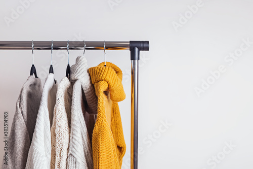 Different woolen knitted sweaters on hangers